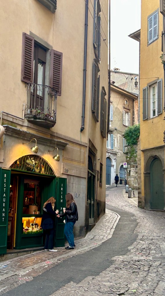 Charming narrow street in Bergamo, Italy, with historic buildings, cobblestone road, and small local restaurant