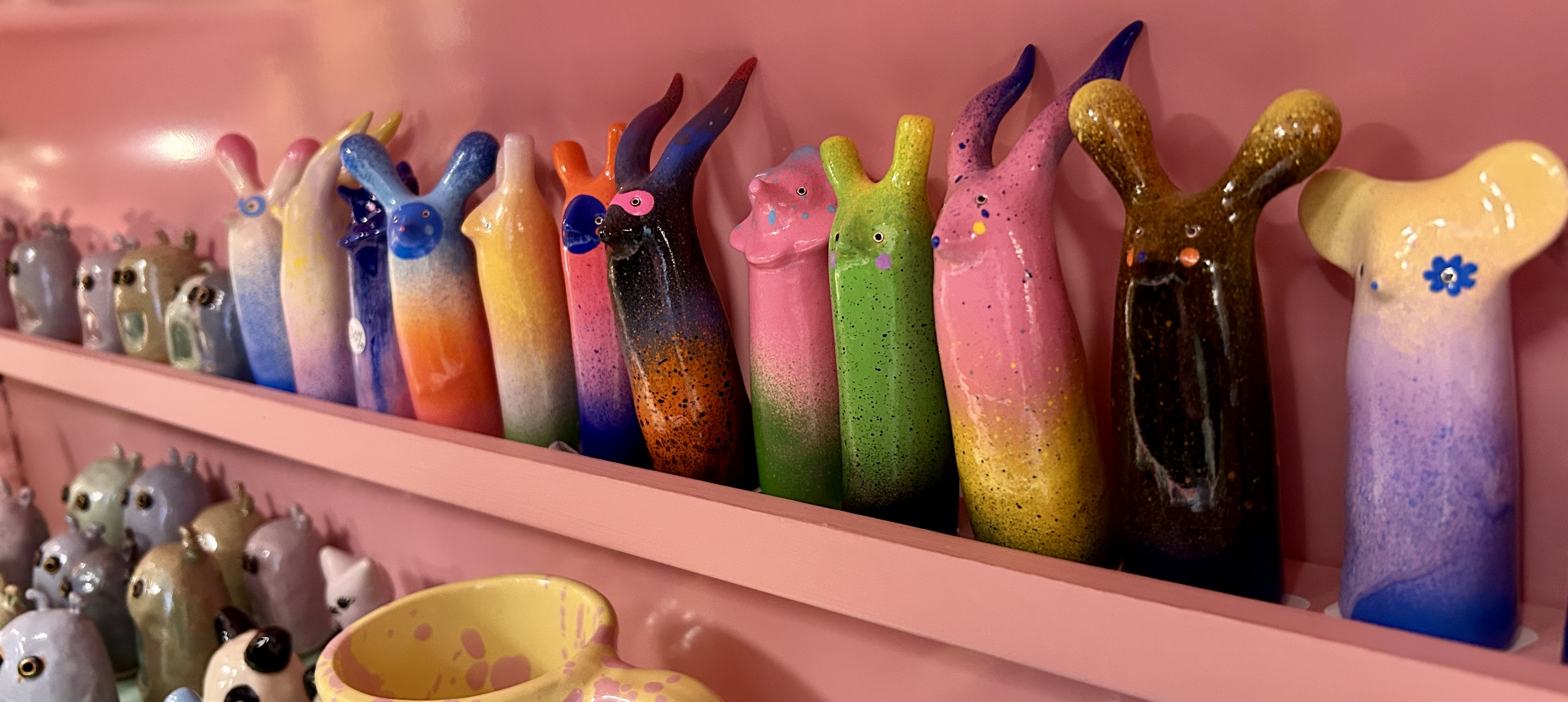Colorful handmade ceramic figures displayed inside a small shop in Haga