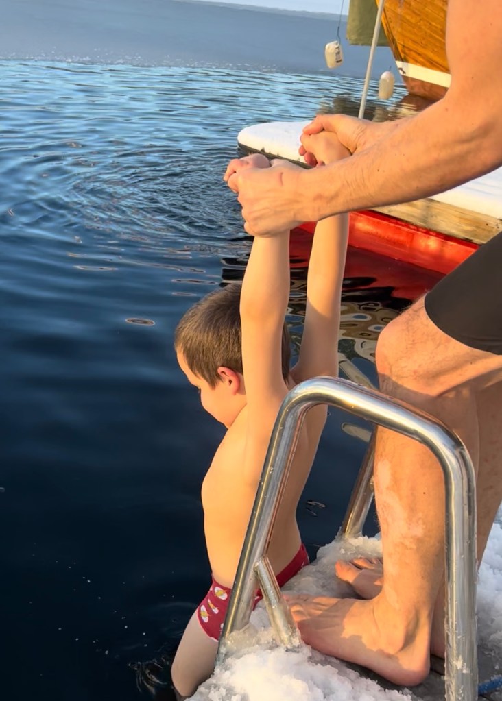 Child trying ice bathing from a snowy dock in Norway