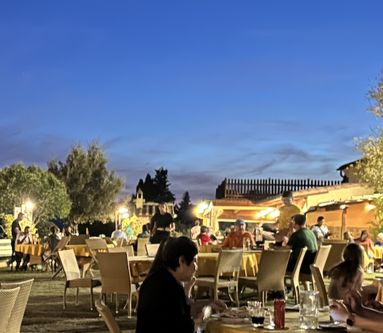 Evening dining at an Italian agriturismo with guests enjoying outdoor dinner.